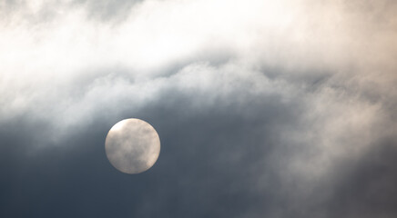 The sun shines behind the clouds during