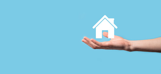 Male hand holding house icon on blue background. Property insurance and security concept.Real estate concept.