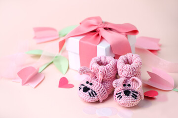 Pair of small funny baby socks with gift box, decorative flowers on pink background with copy space for your warm message, baby shower, first newborn party background, copy space