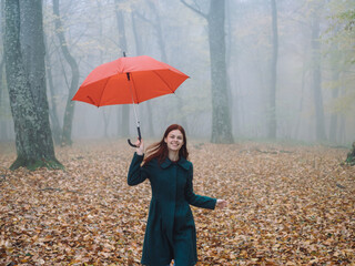Pretty woman with red umbrella in autumn on nature yellow leaves walk
