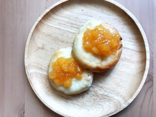 Thin pancakes with orange jam or marmalade on wooden background.