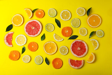 Ripe citrus slices and leaves on yellow background