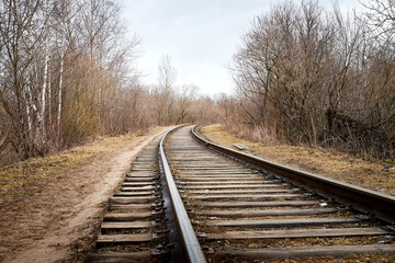 Railway among bare and bald trees on an autumn or spring day
