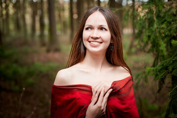 Naklejka premium Beautiful young brunette woman with long hair in a forest pines and firs on a summer day