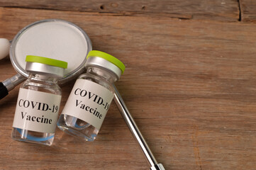 Covid-19 vaccine bottles and stethoscope over wooden background