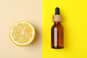 Dropper bottle with oil and lemon on two tone background