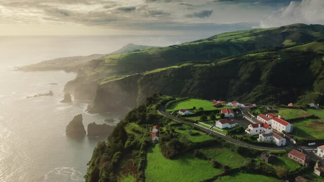 Flores Island, Azores, Portugal. Picturesque coastal settlement with beautiful sunrise in the background. Aerial view of a small village in the heart of a lush valley. High quality 4k footage