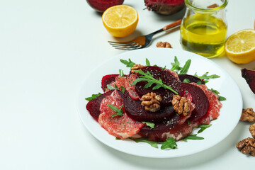 Plate of tasty beet salad and ingredients on white background