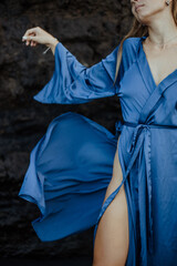 Photoshoot of a blonde girl in a blue dress on the Bali beach with black sand