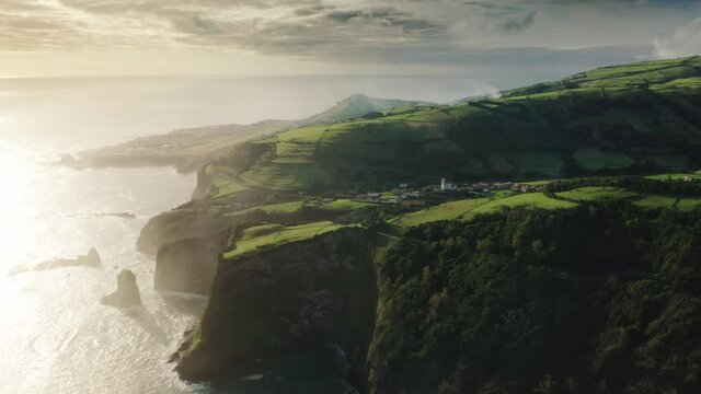 Casa do Gato Tomas, Flores Island, Azores, Portugal. Aerial view of the Jurassic jungle natural landscape. Picturesque coastal village with beautiful sunrise in the background. High quality 4k footage