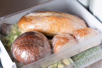 A loaf of wheat bread and other frozen food on a shelf of a home freezer, big procurement and food...