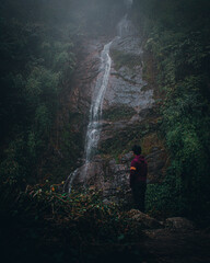 person walking near a mountain waterfall