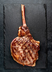 Grilled tomahawk beef steak with spices on stone background