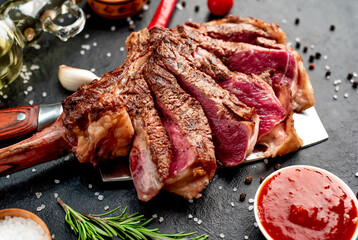 Tomahawk beef steak with spices on a knife on a stone background
