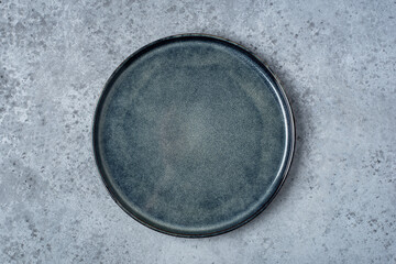 An empty plate on a gray concrete table. Top view.