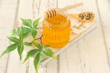 Cannabis honey in a bowl with wooden deeper, hemp leawes amd seeds on wooden table