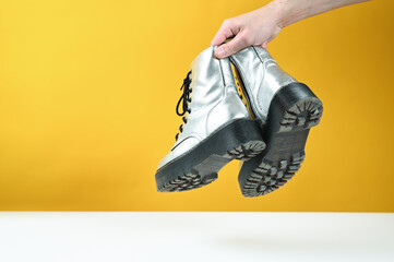Silver shoes in hand, on a yellow background