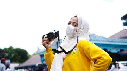 Fototapeta na wymiar an Asian woman traveler in keraton solo wearing jilbab and analog camera