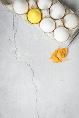 Colored Easter egg and white eggs  with a copy space. Yellow Easter egg colored by turmeric powder .Natural dye for eggs. Easter eggs painted with natural dyes. Turmeric powder on a tea spoon .