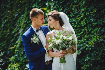 Bride and groom stand face to face against the backdrop of green nature. Happy loving couple on...