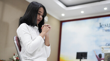 a Christian woman praying humbly in church