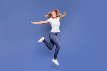 Fototapeta na wymiar Full size profile side photo of young cheerful girl happy positive smile jump up fly hands wings isolated over blue color background