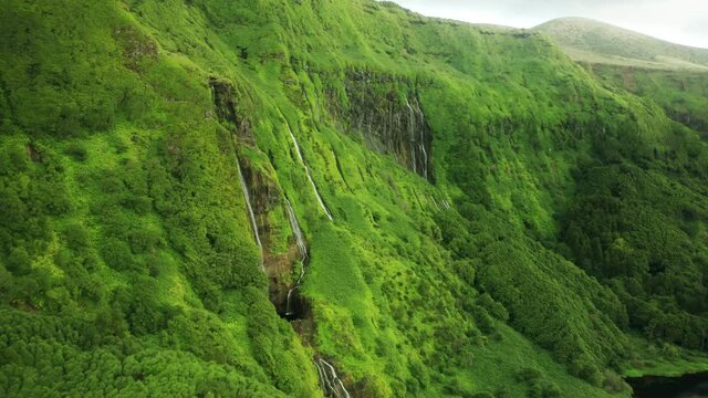 Poco Ribeira do Ferreiro, Flores Island, Azores, Portugal. Amazing rocky cliffs with streaming waterfalls. Aerial footage of untouched natural landscape under cloudless sky. High quality 4k footage