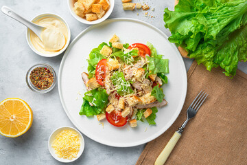 Traditional Caesar salad with croutons and fresh vegetables on a gray background. Top view, horizontal.