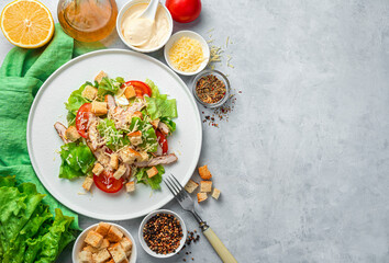 Salad with chicken breast, fresh vegetables, cheese and breadcrumbs on a gray background.