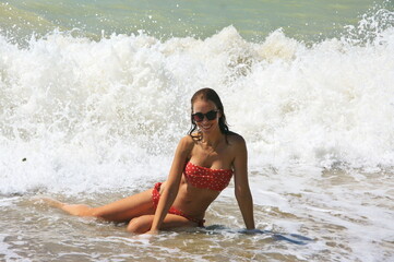 Young woman on sand by sea wave