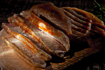 Steak on a wooden board on a black background. Roasted meat on an old shabby table. Contrasting dramatic light as an artistic effect.