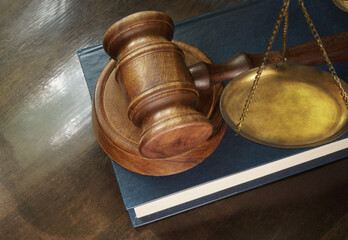 Judge gavel on legal book and brass scale on wooden table, justice and law concept
