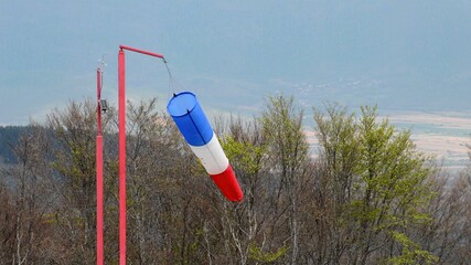 wind sock - red , blue and white pointer indicating strength and direction of the wind against the blue sky