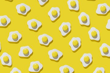 Fried eggs pattern made of paper on a vibrant yellow background. Minimalistic food fashion concept. Flat lay, top view.