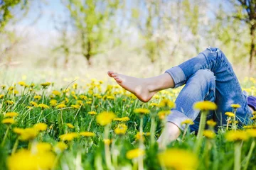 Foto auf Acrylglas Wiese, Sumpf Relaxing girl lying on the spring blooming meadow