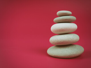 Fototapeta na wymiar A stack of white zen stones on a pink background, minimalism