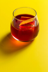 red drink in a glass with ice and orange zest