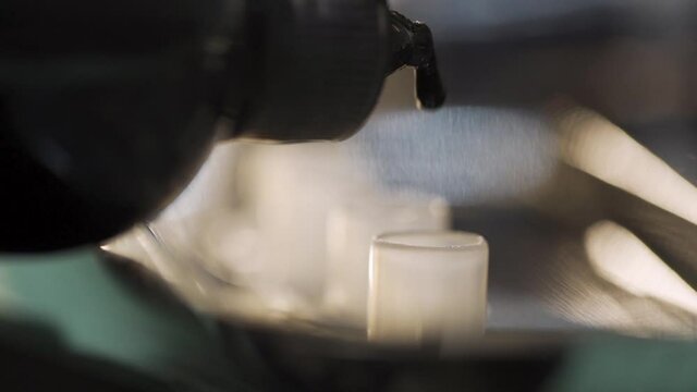 Macro slow motion shot, tattoo artist dropping black ink into the containers. Shot at 120fps.
