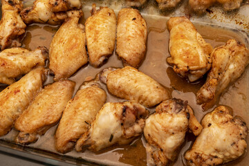 Home roasted chicken wings with honey sauce on a baking tray.