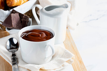 Appetizing breakfast with a delicious cup of thick, drinkable hot chocolate, along with croissants. Homemade look. With copy space.