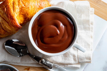 Appetizing breakfast with a delicious cup of thick, drinkable hot chocolate, along with croissants. Homemade look. Top view.