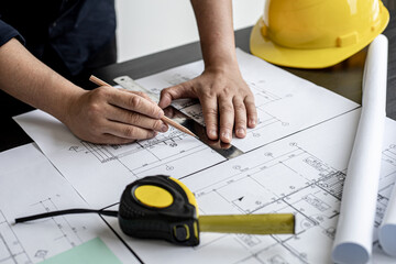 An architect, a home design engineer, is drafting a house plan for a client in his office. He is writing a house plan based on the needs of his clients. House building and interior ideas.