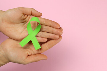 Green ribbon in hand as a symbol of disease awareness, organ transplant