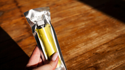 Yellow disposable electronic cigarette in packing in female hand