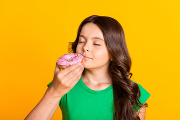 Photo of young lovely pretty charming little girl smelling doughnut enjoying dessert isolated on...