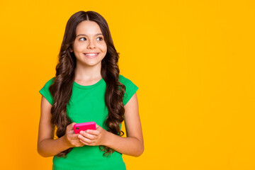 Photo of happy good mood cheerful lovely hispanic girl look copyspace dreaming use phone isolated on yellow color background