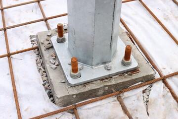Fixing the iron pillar to the concrete foundation with bolts and nuts close-up