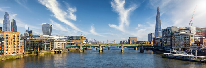 Panoramic view of the London skyline along the Thames river with Southwark Bridge and Tower Bridge during a sunny day