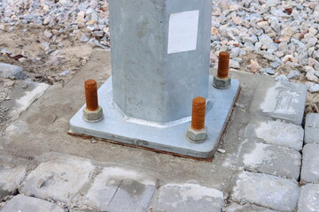 Fixing the iron pillar to the concrete foundation with bolts and nuts close-up