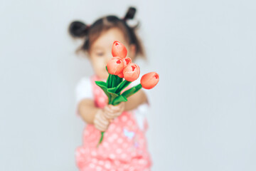 Girl standing in front of white background and holding tulips in her hands